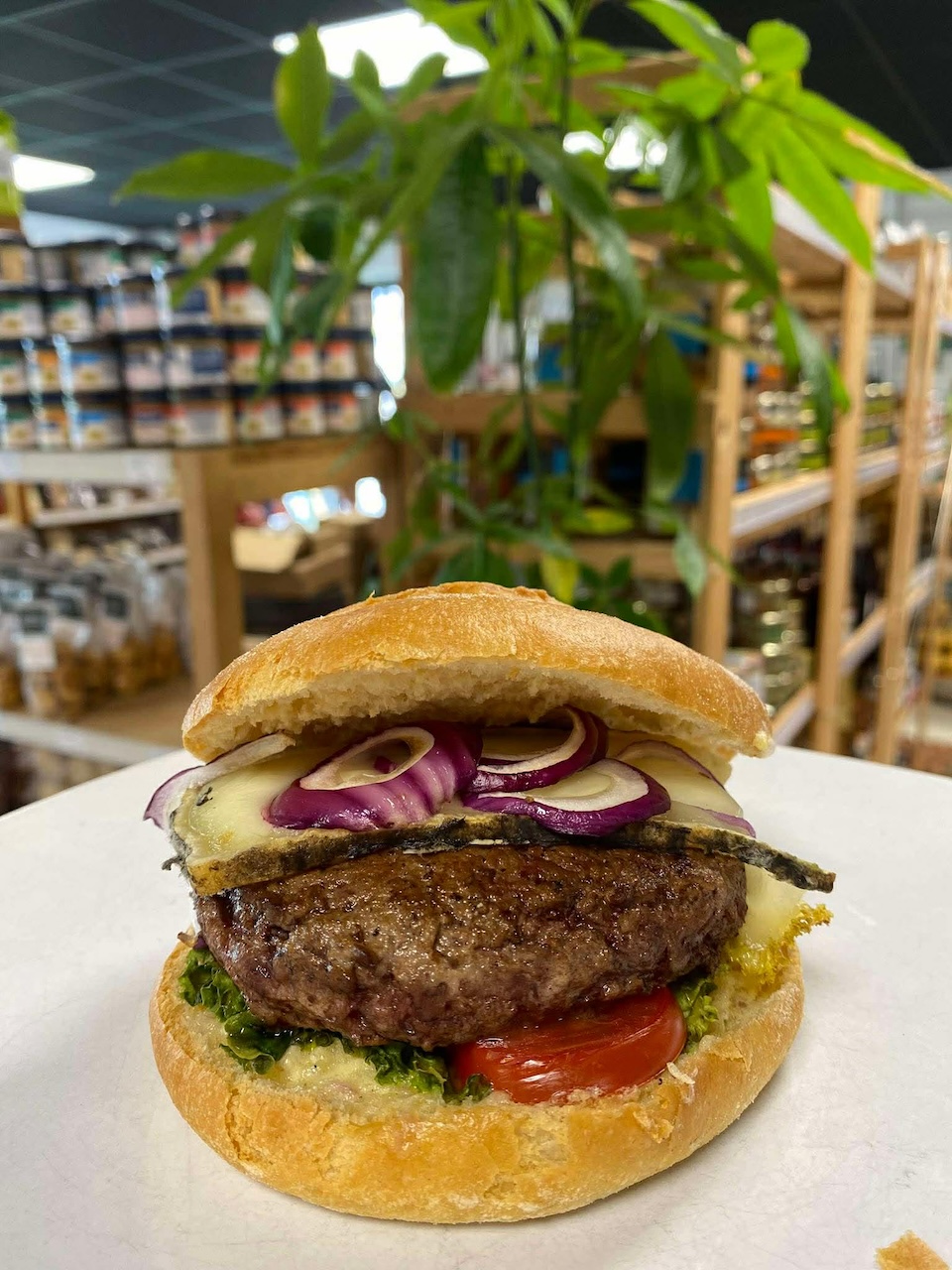 Gros plan sur un burger sur un comptoir avec en fond les étagères d'Au Marché de l'Oust